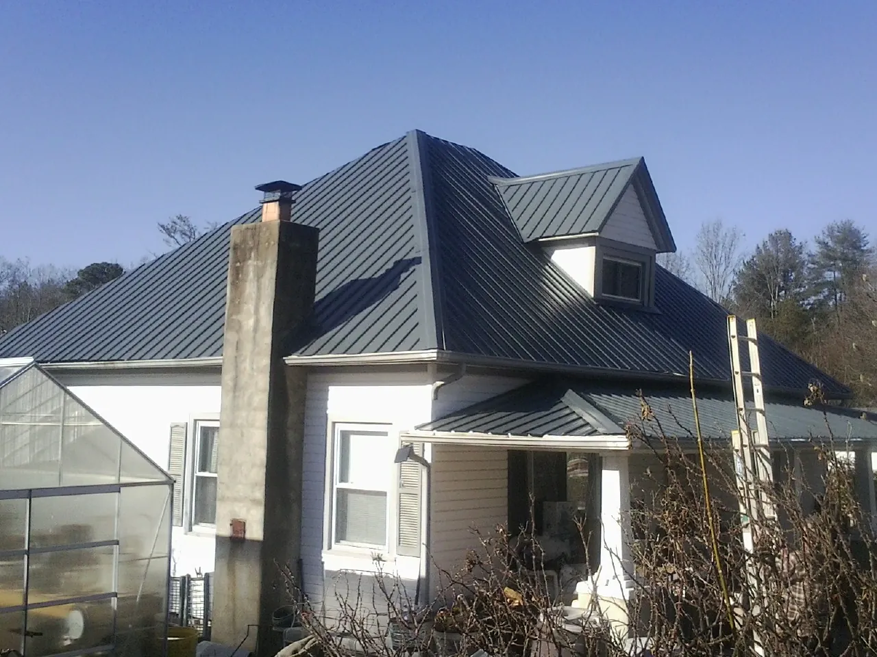 Dark blue standing seam metal roof on a white farmhouse with dormer — Slate & Tile Roof Repair by Roofing Brothers in Streator