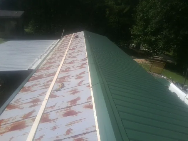 Old rusted panels beside newly installed green metal roofing — Wind Damage Roof Repair by Roofing Brothers in Streator