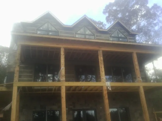 Dormers and porch framing on a large log home under construction — Roof Coating work by our crew in Streator