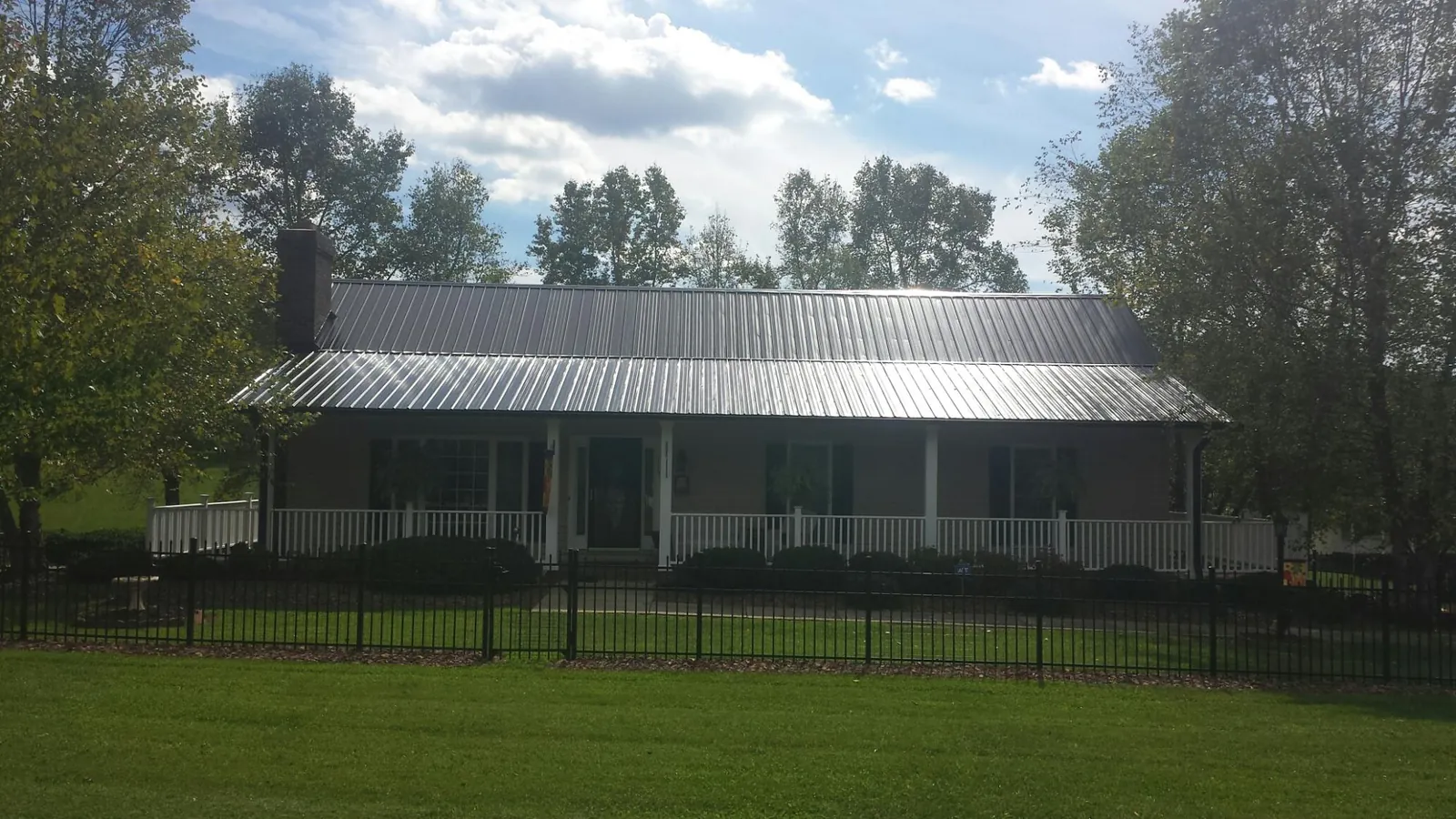 Gray metal roof on a brick ranch with a full width front porch — Gutter Guard Installation work by our crew in Streator