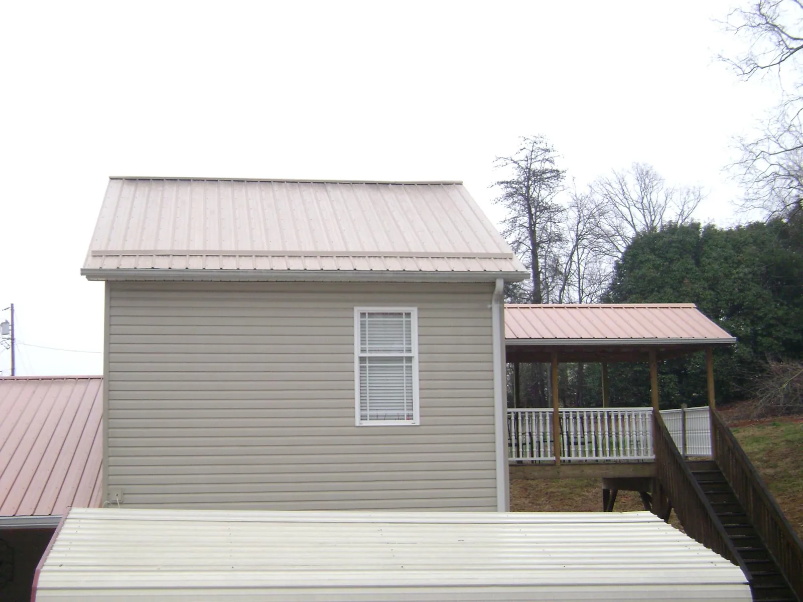 Tan metal roofs on a two story addition and attached porch, from a Roof Replacement job in Streator