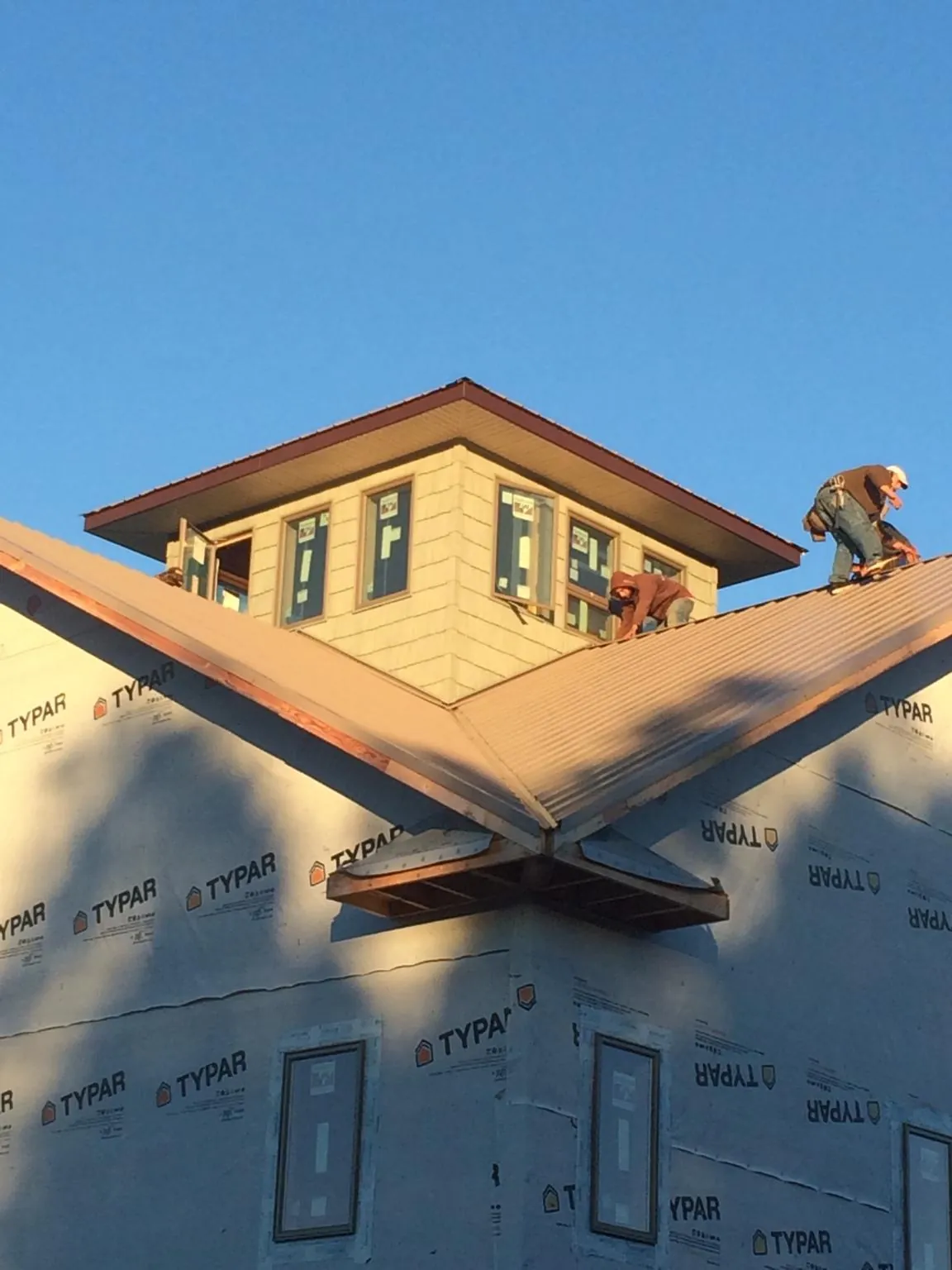 Roofers working around a rooftop cupola on a new metal roof at sunset — Roof Waterproofing in Streator by Roofing Brothers